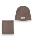 Zestaw czapka beanie i komin dla chłopca - bawełna, prążek, wiosna marki PanPan 35 jest ułożony płasko na białym tle. Brązowa czapka z prążkowanej dzianiny ma białą naszywkę z napisem TALENT IS POWER z małym tekstem pod spodem.