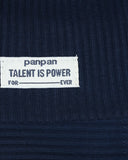 Biała materiałowa metka na granatowym prążkowanym materiale z napisem "PanPan 35 TALENT IS POWER FOR EVER" w czarnych czapkach - idealna do Zestawu czapka beanie i komin dla chłopca (bawełna, prążek, wiosna) marki PanPan 35.