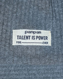 Biała materiałowa metka na szarej prążkowanej bawełnie koszulki PanPan 35 wiosenny zestaw czapka beanie i komin dla chłopca brzmi: panpan TALENT IS POWER FOR ____ EVER czarnym tekstem, z pustym miejscem między FOR i EVER.