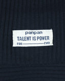 Biała materiałowa metka na ciemnym prążkowanym materiale z napisem "panpan TALENT IS POWER" z "FOR" i "EVER" oddzielonymi linią, umieszczona na PanPan 35 zestaw czapka beanie i komin dla chłopca - bawełna, prążek, wiosna.