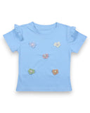 Bawełniany T-shirt dla dziewczynki PanPan 35 w kolorze jasnoniebieskim, z kwiatkami 3D i falbanką na rękawkach, wykonany ze 100% bawełny. Koszulka leży płasko na białym tle.