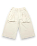 Wiosenne spodnie z szeroką nogawką z mankietami dla dziewczynki PanPan 35 z miękkiej bawełny 100%-eleganckie, kremowe, z elastycznym pasem, plisami i kieszeniami po bokach. Idealne na wiosnę. Zdjęcie na białym tle.