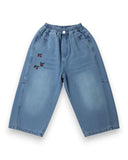 Jeansy dziewczęce z szeroką nogawką i haftowanymi wisienkami PanPan 35 to modne, niebieskie spodnie na gumce z kieszeniami, haftem na lewym udzie i jasnym przetarciem z przodu oraz luźnym krojem.