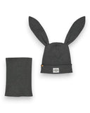 PanPan 35 Zestaw czapka z uszami królika i komin - bawełna, prążek zawiera szarą czapkę z długimi uszami królika i naszywką z twarzą z kreskówki, a także pasujący szary ocieplacz na szyję, oba ułożone płasko na białym tle.